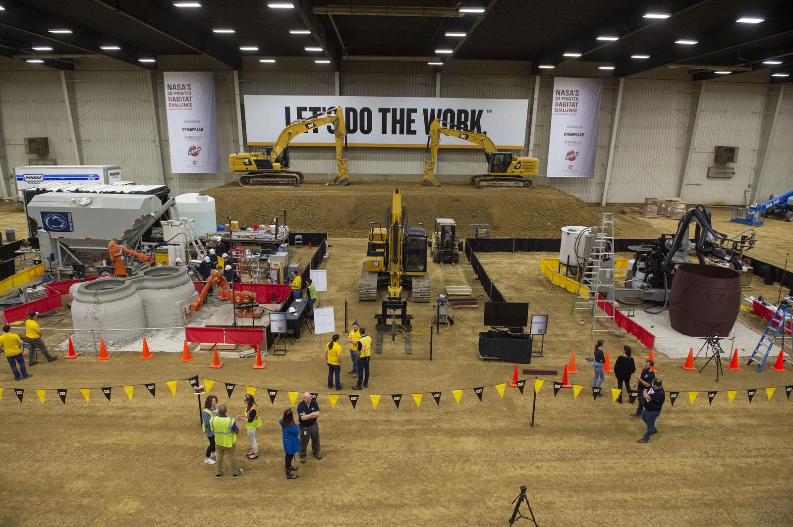 Two large gantry 3D printers extrude curved concrete walls of subscale habitat structures side by side at NASA's 3D-Printed Habitat Challenge. Real NASA photograph used on the Ellis Abel Learns "Why I Love 3D Printing" page.
