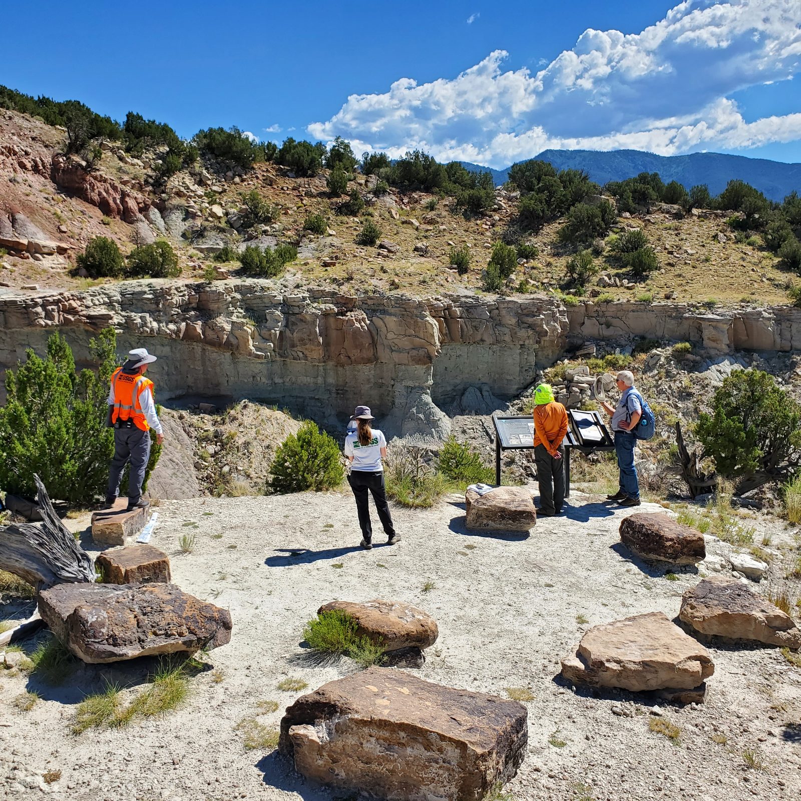 Someone working in Dinosaurs — Ellis Abel Learns A USGS field crew stands at an overlook above the Marsh-Felch dinosaur quarry while flying a drone to map the site. Real USGS photograph used on the Ellis Abel Learns "Why I Love Dinosaurs" page.