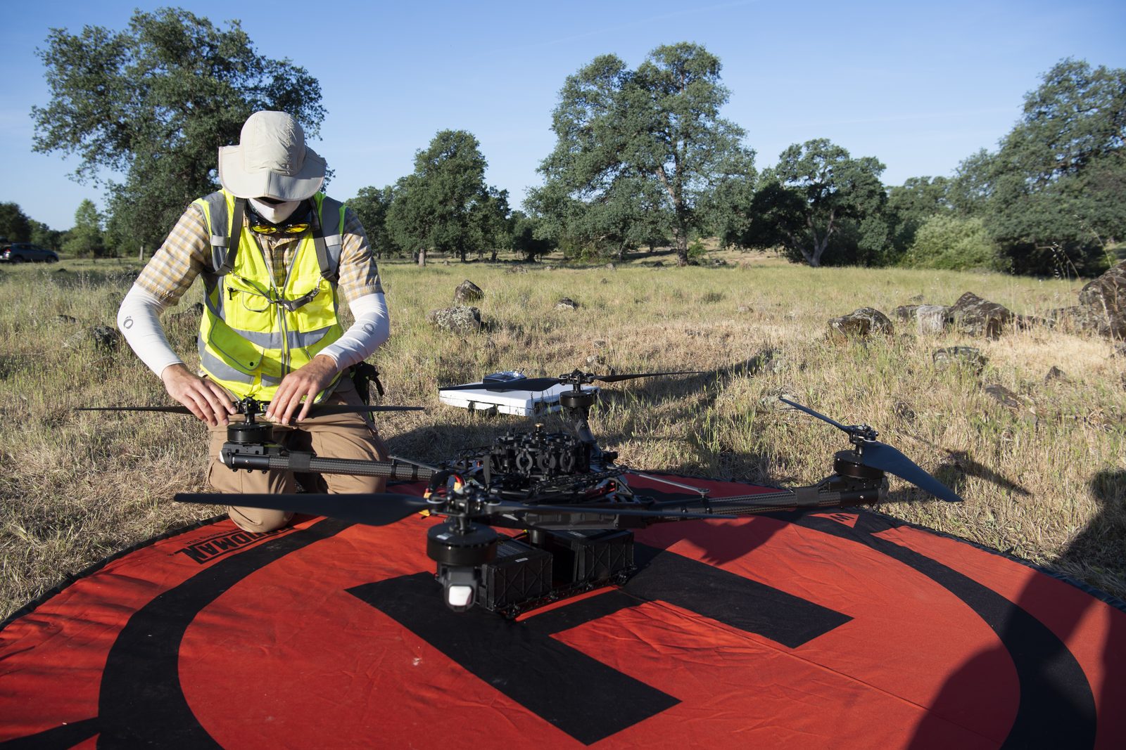 Someone working in Drones — Ellis Abel Learns Pilot Jonas Jonsson kneels on the ground performing pre-flight checks on an Alta X drone during Cal Fire training exercises. Real NASA photograph used on the Ellis Abel Learns "Why I Love Drones" page.