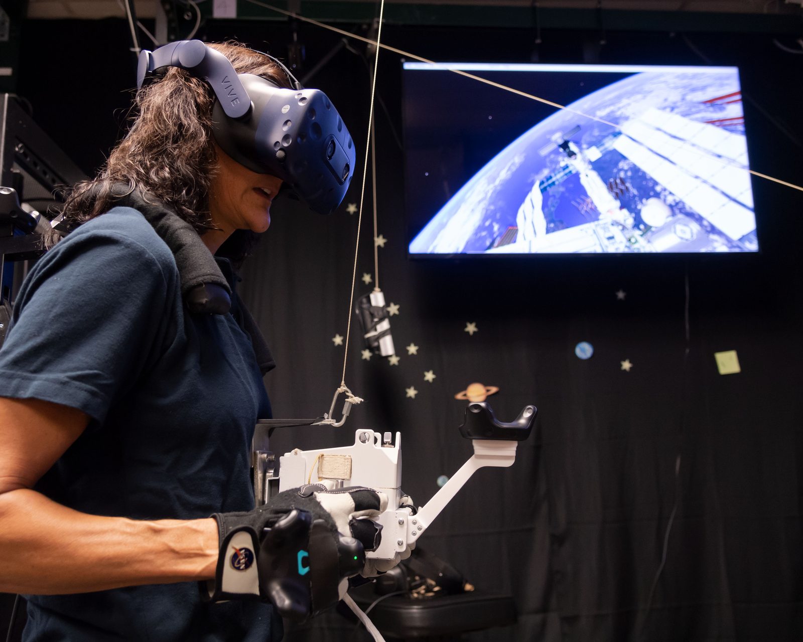 Someone working in Space — Ellis Abel Learns Astronaut Suni Williams, wearing a virtual-reality headset and gloves, practices spacewalking in the Virtual Reality Lab at Johnson Space Center. Real NASA photograph used on the Ellis Abel Learns "Why I Love Space" page.